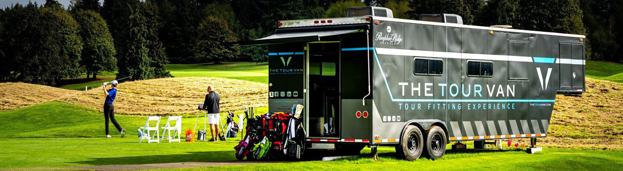 A golf fitting experience with a tour van on a course, featuring golfers and equipment in a scenic setting.