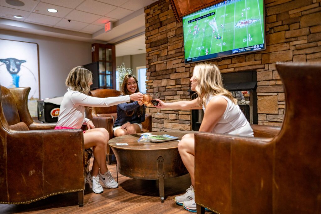 Three women enjoying a beverage around a cozy recreation room